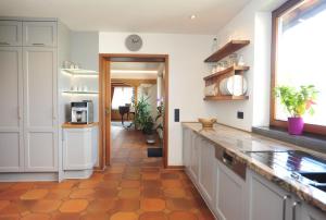 uma cozinha com armários brancos e piso em azulejo em Casa Cara em Baiersbronn