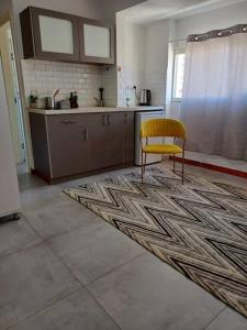 a kitchen with a yellow chair sitting on a rug at סטודיו עידן in Tel Aviv