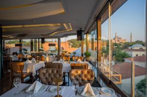 un restaurante con mesas y sillas blancas y ventanas en Hotel Olimpiyat, en Estambul