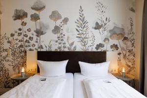 2 Betten in einem Zimmer mit Blumen an der Wand in der Unterkunft Flair Hotel zum Storchen in Bad Windsheim