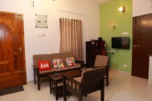 een woonkamer met een tafel en stoelen en een televisie bij Mahabs homestay Villa in Mahabalipuram