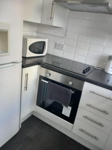 a kitchen with a stove and a microwave at Humber Maisonette Airy, Modern & Chic! in Goole