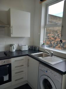 a kitchen with a sink and a washing machine at Humber Maisonette Airy, Modern & Chic! in Goole