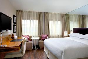 ein Hotelzimmer mit einem großen Bett und einem Schreibtisch in der Unterkunft Sheraton Grand Hotel & Spa in Edinburgh