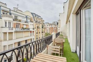 a balcony with wooden benches and buildings at Rent a Room apartments - Degas in Paris