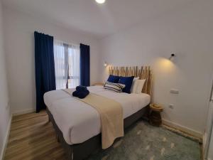 a bedroom with a large bed with blue pillows at Bel Air Surf Escape in El Cotillo