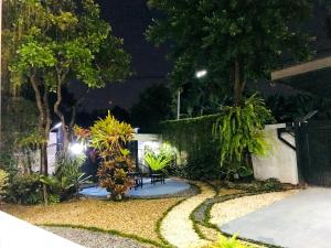 a garden at night with a bench and trees at MeeTHan House in Chiang Mai