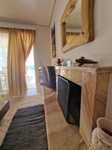een woonkamer met een open haard en een spiegel bij Sea Front Villa near Athens in Isthmia