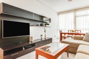 Home2Book Comfy Apartment Las Palmas Center Triana في لاس بالماس دي غران كاناريا: غرفة معيشة مع تلفزيون وأريكة وطاولة