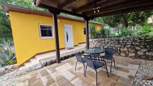 a patio with a table and chairs and a yellow wall at Urinj in Kostrena