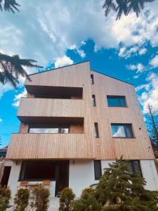 a building with a wooden roof on top of it at NORDIC Apartamente Păltiniș in Păltiniş