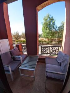a balcony with two chairs and a table and two windows at Jannat azaytoun in Marrakesh