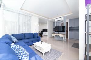 ein Wohnzimmer mit einem blauen Sofa und einem weißen Tisch in der Unterkunft 2bdr Apartment near Surin beach #302 in Ban Lum Fuang