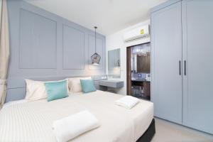 ein weißes Schlafzimmer mit einem großen weißen Bett mit blauen Kissen in der Unterkunft 2bdr Apartment near Surin beach #302 in Ban Lum Fuang + 14 Fotos