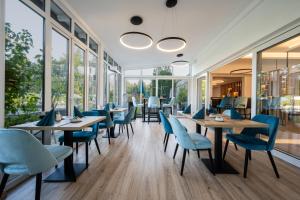 ein Restaurant mit blauen Stühlen, Tischen und Fenstern in der Unterkunft Hotel Villa Flora in Velden am Wörthersee
