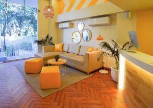 a living room with a couch and orange chairs at Bloom Hotel - Magarpatta in Pune