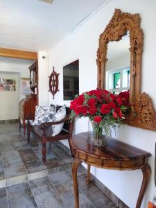 um espelho e um vaso de flores vermelhas sobre uma mesa em Big Skies Guesthouse em Gordonʼs Bay