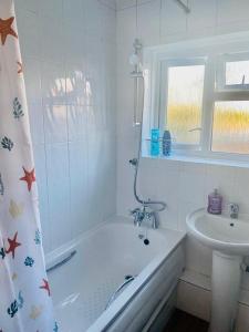 Baño blanco con bañera y lavamanos en Wonderful Apartment in London en The Hyde
