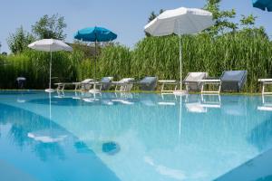 einen Pool mit Tischen, Sonnenschirmen und Stühlen in der Unterkunft Hotel Villa Flora in Velden am Wörthersee