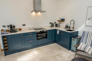 eine Küche mit blauen Schränken und einer Spüle in der Unterkunft Lily Cottage - 1 bedroom in Forres