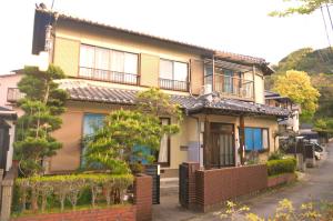 uma casa amarela com uma cerca na frente em 花源 em Beppu
