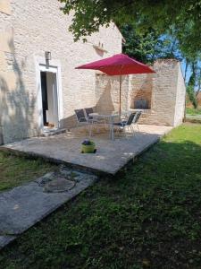 uma mesa e cadeiras sob um guarda-sol num pátio em La petite maison em Matha