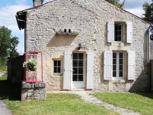 um antigo edifício de pedra com portas e janelas brancas em La petite maison em Matha