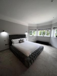 um quarto com uma cama grande com lençóis brancos e janelas em Luxury apartment Berkshire em Binfield