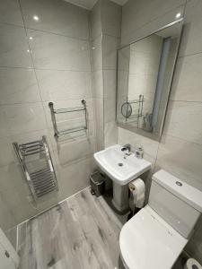 a bathroom with a sink and a toilet and a mirror at Southbank Stays Premium Apartment - Sleeps 4 in Coventry