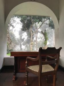 a chair sitting in front of a window with a piano at Dunwatta House in Kandy