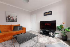 a living room with an orange couch and a television at Home away from home in Sheffield