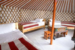 una habitación con 2 camas y una mesa en una yurta en Dalain chimeg Resort Khuvsgul Province, Mongolia, 