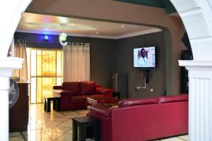 een woonkamer met twee rode banken en een tv bij BBD Hotel And Suites in Ibadan