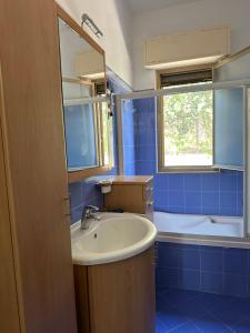 ein blau gefliestes Badezimmer mit Waschbecken und Badewanne in der Unterkunft Villa San Leo in San Leone + 14 Fotos