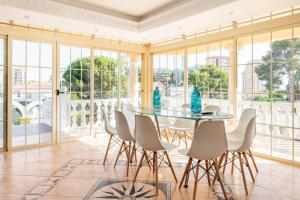una sala da pranzo con tavolo in vetro e sedie bianche di Villa Constantinos apartamentos o villa completa a Calpe