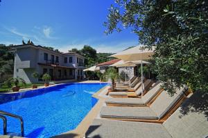 a swimming pool with lounge chairs next to a house at Mavi Deniz Konuk Evi in Selimiye