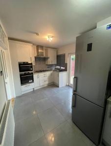 a kitchen with white cabinets and a refrigerator at The Peaceful Place in Cheshunt
