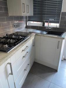 a kitchen with white cabinets and a stove and a sink at The Peaceful Place in Cheshunt