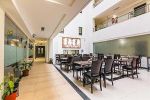 una sala da pranzo con tavoli, sedie e lavagna di Magnus Square Business Hotel a Pune