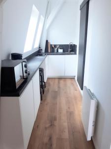 een keuken met witte kasten en een houten vloer bij "Au pied du Beffroi" - Superbe emplacement in Arras