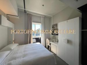 een slaapkamer met een wit bed en een bureau bij PORTOFINO SUITE VISTA MARE CON SPIAGGIA PRIVATA in Portofino