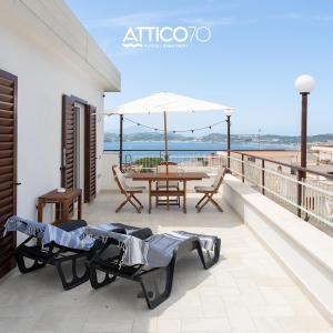 - un balcon avec une table, des chaises et un parasol dans l'établissement Attico 70 - Puteoli Apartament, à Pouzzoles
