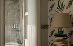 a bathroom with a shower and a lamp and books at The Millstone, Mellor in Blackburn