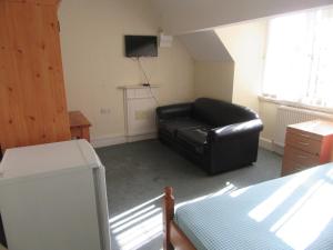 a living room with a black leather couch and a television at RK Heritage House in Birmingham