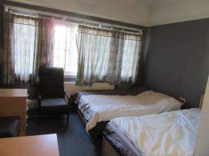 a bedroom with two beds and a chair and a window at RK Heritage House in Birmingham