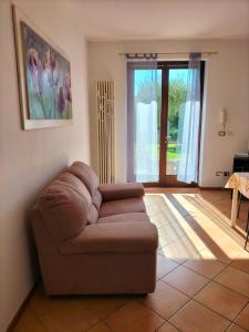 a living room with a brown couch in front of a door at Casa Degli Ulivi in Lazise