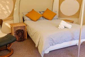 a bedroom with a large bed with orange pillows at South Devon Luna Bell Tent in Newton Abbot +17 photos