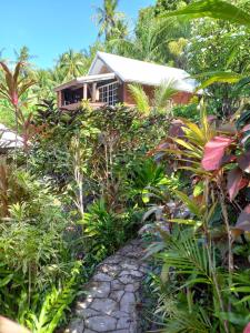 a house in the middle of a jungle with a stone path at Pension LE PASSAGE vu mer in Vaitoare