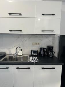 una cocina con armarios blancos y fregadero en Kato Zaros Apartments, en Zarós