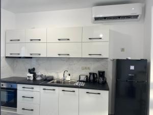 uma cozinha com armários brancos e um frigorífico preto em Kato Zaros Apartments em Zarós